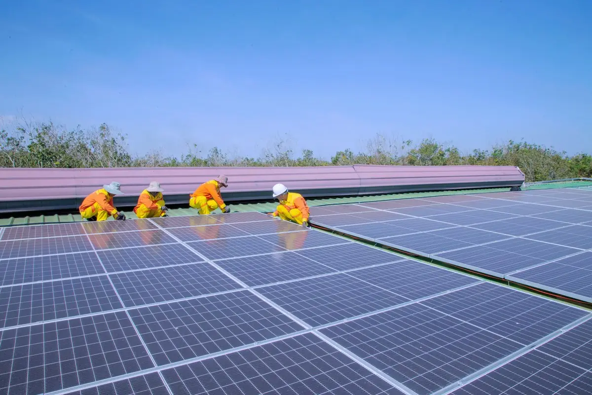 Instaladores montando placas de energia solar no telhado de um galpão