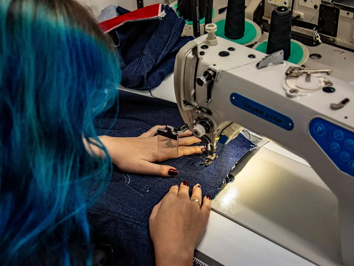 Costureira numa máquina de costura industrial em oficina de confecção